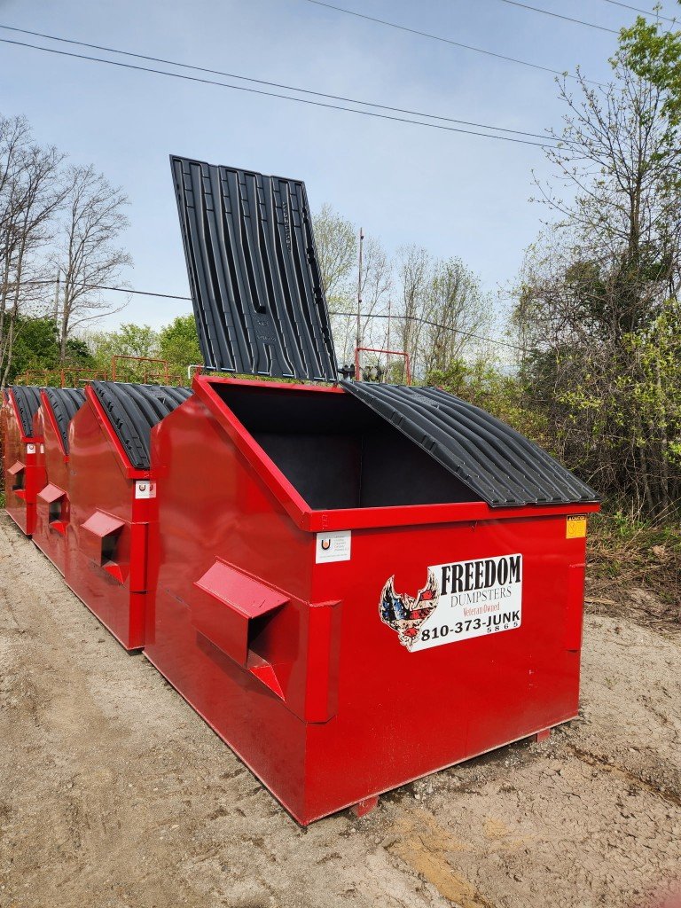 Red Freedom Dumpsters front-load business dumpsters with Veteran Owned branding and 810-373-JUNK phone number